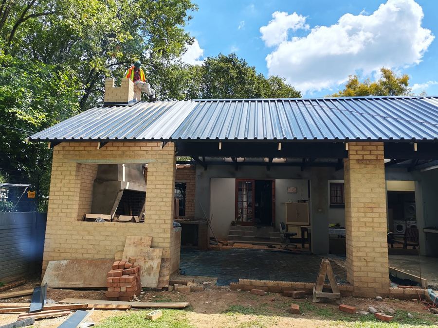Workers installing black steel roof trusses for a braai and entertainment room addition in Pretoria
